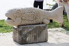 "Petrified Fish", limestone, by Tim DeChristopher stood on a concrete slab soon to be re-occupied by a park bench.
