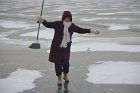 Betsy Leondar-Wright wearing boots plays solo broom hockey on the Spy Pond ice
