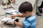 Sam reached into the tube to pull the mast stick through the bark to make his boat.