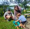 Removing grass between the cobblestones around the picnic table and putting it in the mini-wheelbarrow was a family affair for Adam, Sara, and 4 yr. old Isaac Siegel.