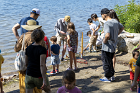 People gathered around Brad Barber launching bark boats at North Beach and learning how to use a Secchi Disc to assess water quality.